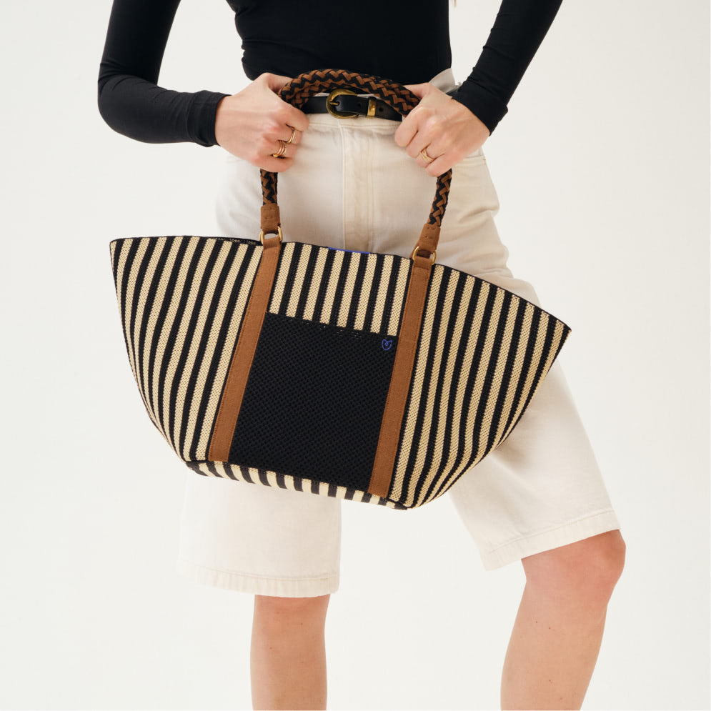  Black and white striped tote bag made from fabric, featuring a spacious design and sturdy handles for easy carrying. 